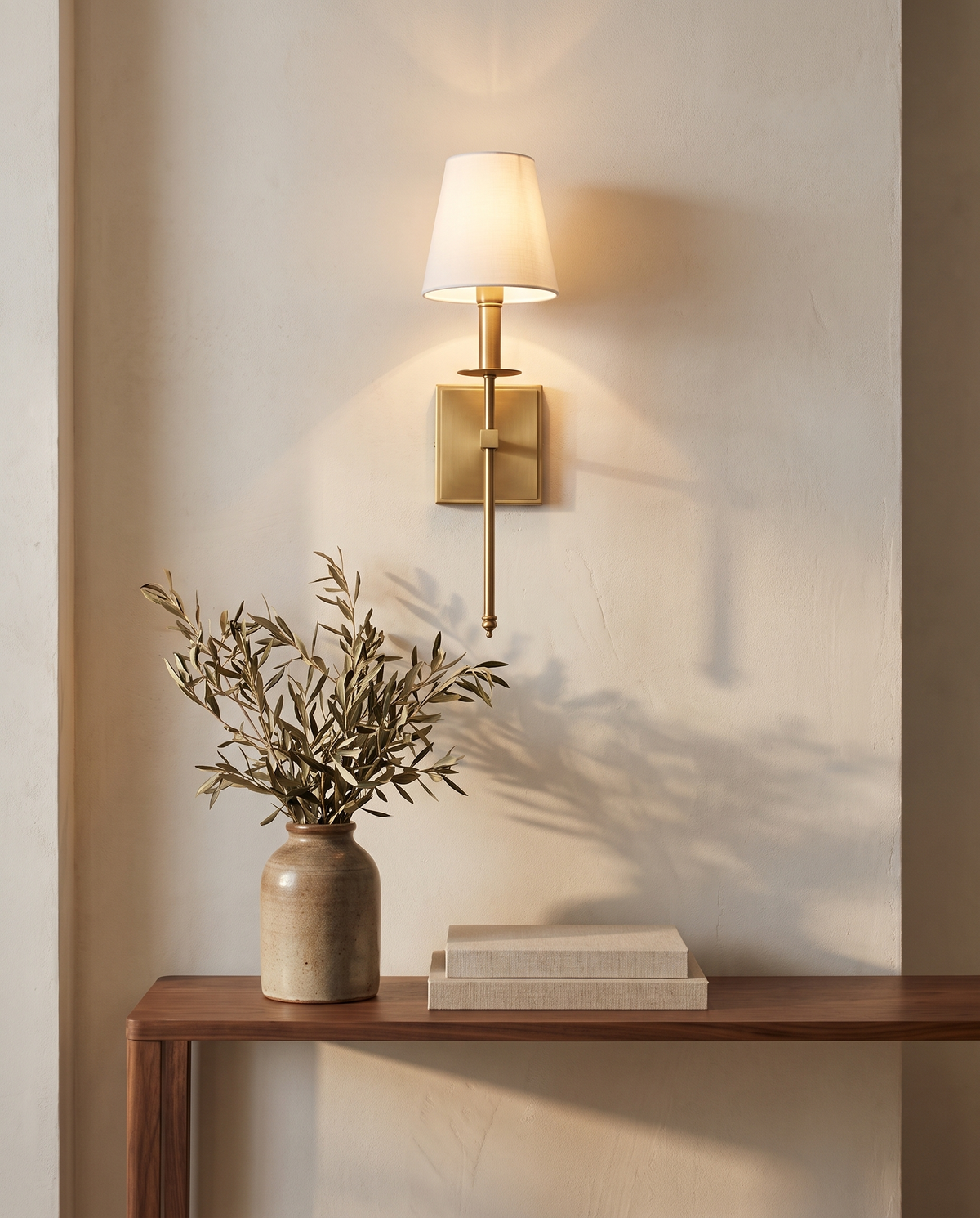 Messing wandlamp met stoffen kap boven een walnoten sidetable