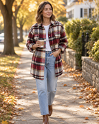 Red plaid flannel shacket worn open over a white tee and jeans
