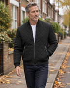 Man wearing the black diamond quilted bomber jacket over a white tee on an autumn street